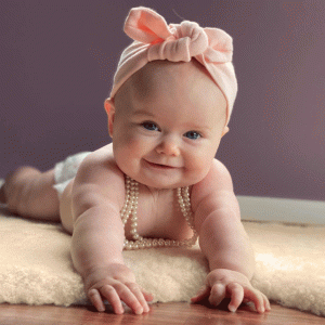 Smiling baby girl lying on her belly on a lambskin rug