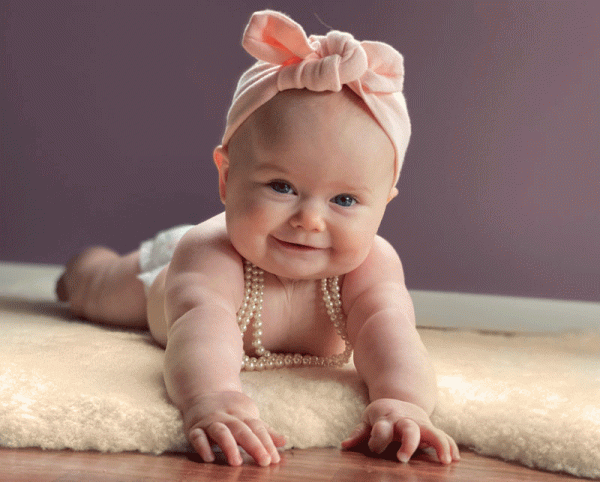 Smiling baby girl lying on her belly on a lambskin rug