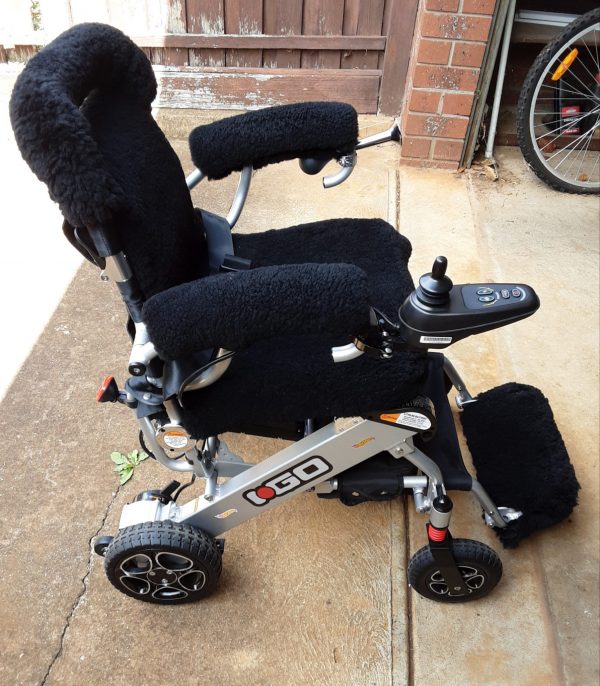 A wheelchair with custom sheepskin covers in black