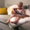 Young girl playing ukelele on long wool lambskin rug