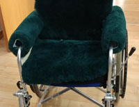 Wheelchair with dark green sheepskin covers