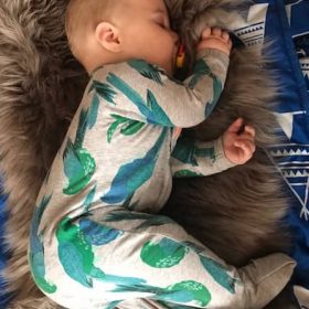 Baby lying on side on coffee coloured long wool rug